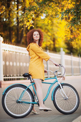 Beautiful young woman riding on bicycle in a park