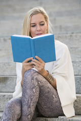 woman sitting on stairs and reading a book