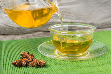 Pouring tea into cup of tea on green bamboo mat