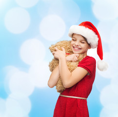 smiling girl in santa helper hat with teddy bear