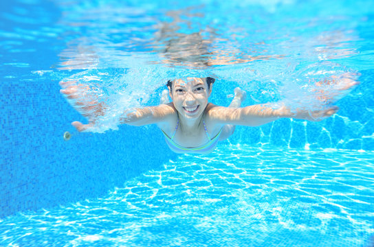 Happy active underwater child swims in pool, kids sport