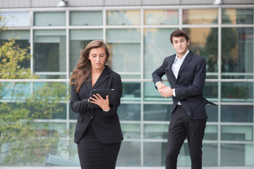 Young business couple with modern building behind  with tablet