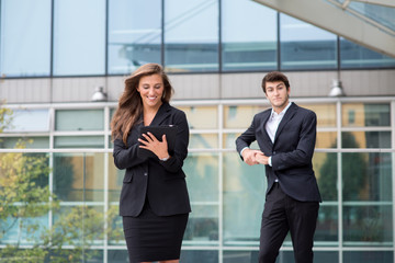 Young business couple with modern building behind  with tablet