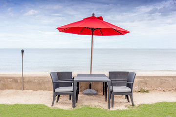 The table set, beach chairs and red umbrella with beautiful beac