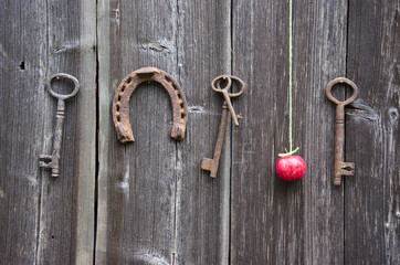 ancient key, horseshoe and red apple on old wooden wall