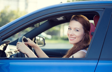 Happy smiling woman, buckled up, driving new car
