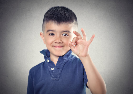 Boy showing ok hand sign, gesture, happy child, grey background 