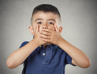 Boy closing, covering mouth with hands speak no evil concept