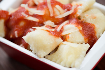 Cheese ravioli with tomato sauce and parmesan, close-up