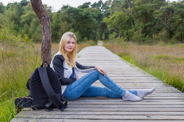 Blonde girl resting on wooden path in nature