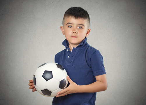 Boy holding football ball  isolated on grey wall background 