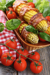 Grilled bacon wrapped corn on table, close-up