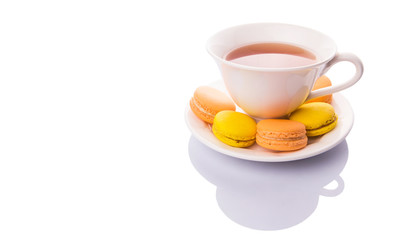 A cup of tea and yellow and orange colored macarons 