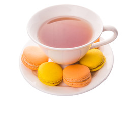 A cup of tea and yellow and orange colored macarons 