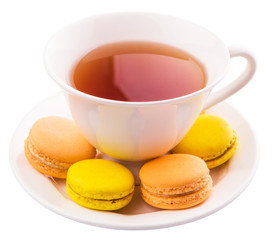 A cup of tea and yellow and orange colored macarons 