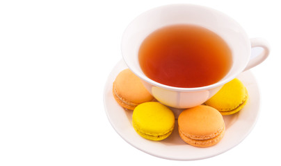 A cup of tea and yellow and orange colored macarons 