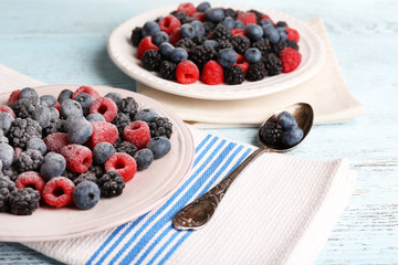 Iced berries on plate, on color wooden background