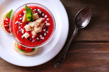 Gazpacho soup in glass bowl, on color wooden background