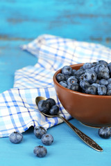 Tasty ripe blueberries in bowl, on wooden table