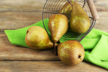 Ripe pears in basket, on wooden background