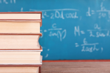 Books on wooden table on blackboard background