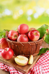 Sweet apples in wooden basket on table on bright background