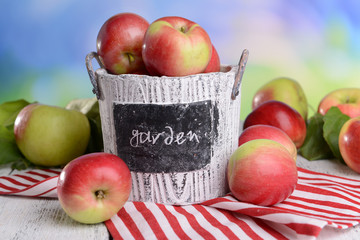Sweet apples in basket on table on bright background