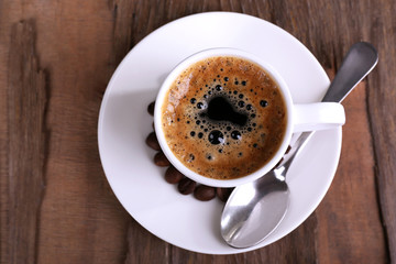 Cup of coffee and coffee beans on wooden background