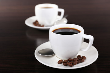 Two cups of coffee and coffee beans on dark background