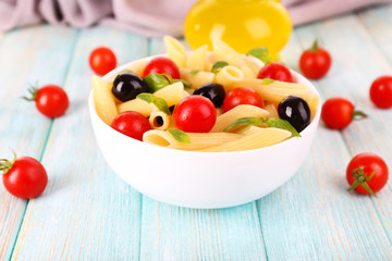 Fototapeta na wymiar Pasta with tomatoes, olives and basil leaves in bowl and napkin