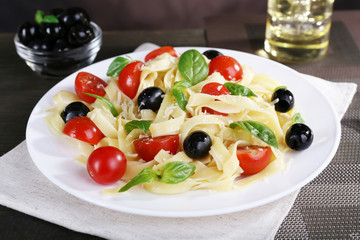 Spaghetti with tomatoes, olives and basil leaves
