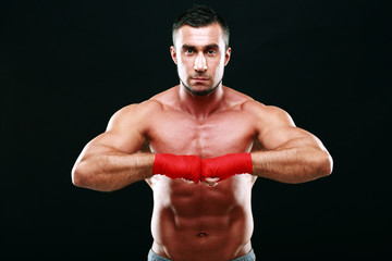 Fototapeta na wymiar Portrait of a muscular man in red gloves on a black background