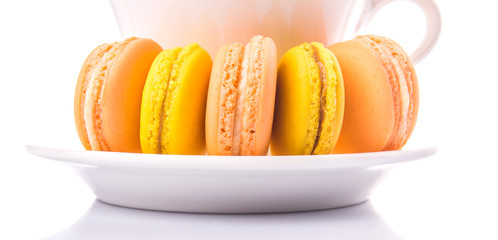 A cup of tea and yellow and orange colored macarons 