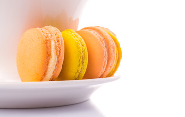 A cup of tea and yellow and orange colored macarons 