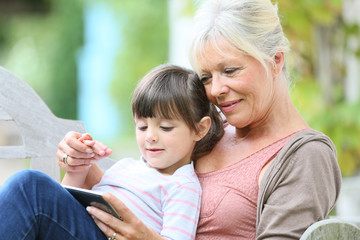 Senior woman with grandkid playing game on smartphone