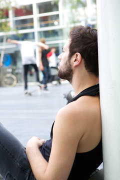 Young man with beard sitting outdoors