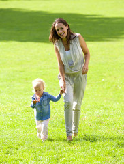 Smiling mother and daughter walking on grass
