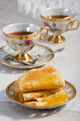 thin pancakes on a plate and cup of tea