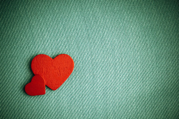 Red wooden decorative hearts on green cloth background.