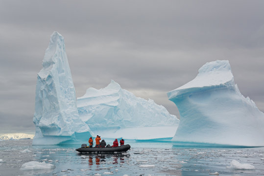 People in inflatible zodiac rib boats passing icebergs at Antarctic Peninsula.