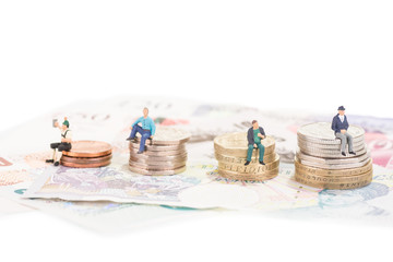 Miniature people sitting on coins close-up