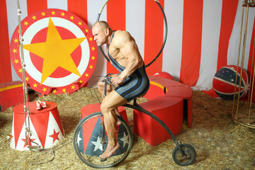 Athlete with grimace riding circus retro bike