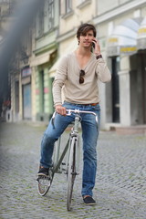 Young man riding a fixie bike and using his smart phone