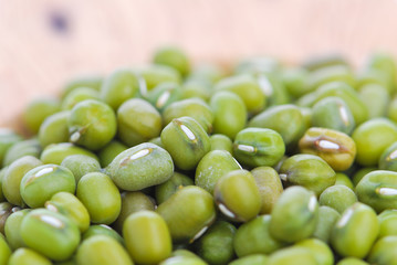 Mung beans on wooden spoon or bowl close up