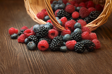 different berries in a basket on a wooden table