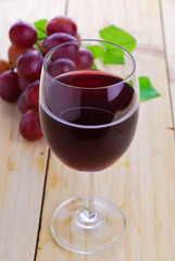 Glass filled with Red Grape Juice  and ripe sweet grape fruit on