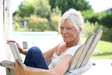 Senior woman reading book by swimming-pool