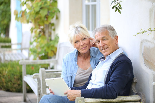 Senior Couple Websurfing On Internet With Tablet