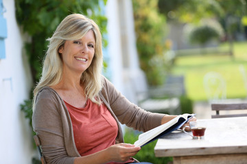 Mature woman reading book in backyard