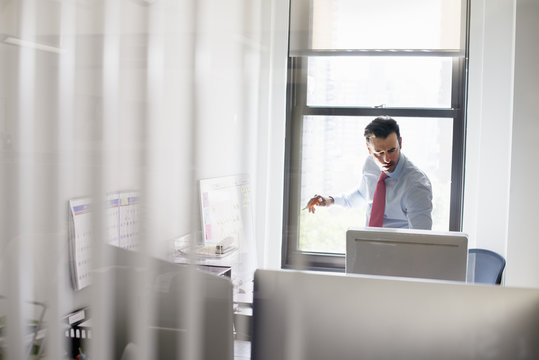 A man standing over a desk looking at a computer screen.